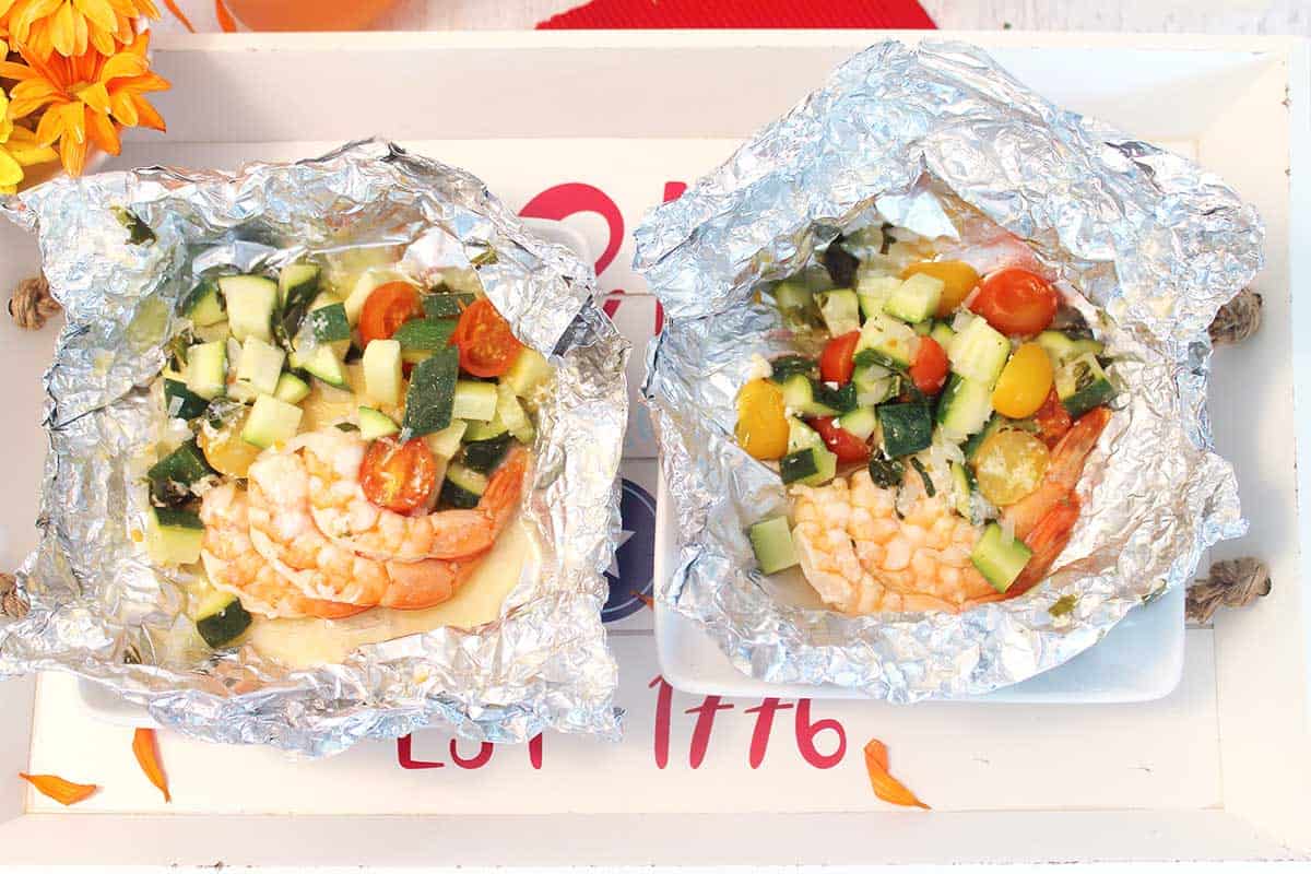Two grilled shrimp packets opened on tray