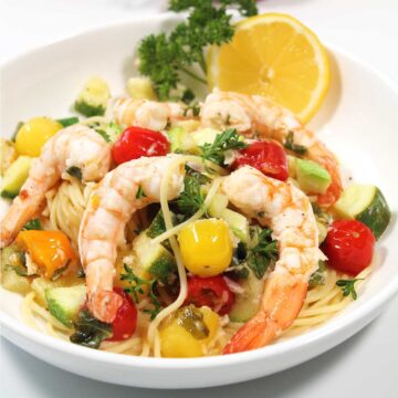 Closeup of grilled shrimp with vegetables over pasta.