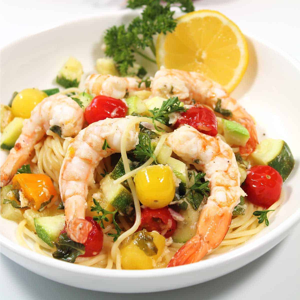 Closeup of grilled shrimp with vegetables over pasta.