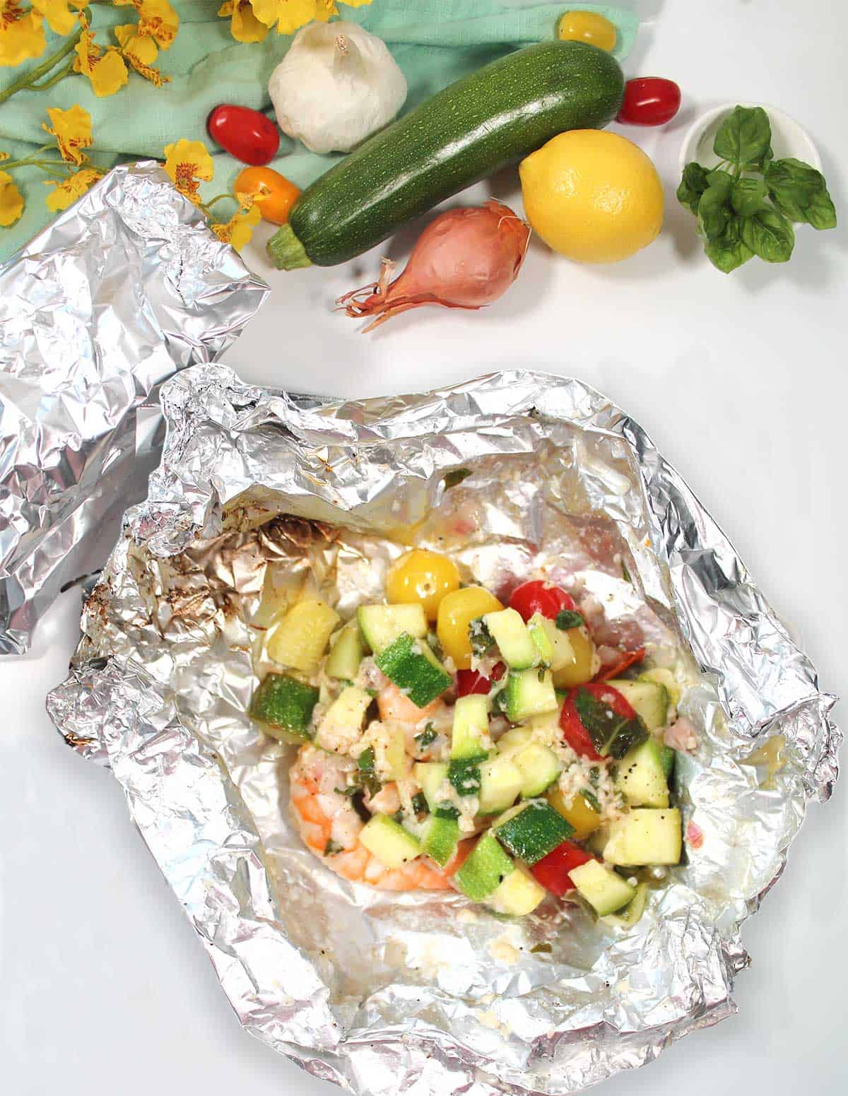 Grilled shrimp foil packets opened on table.