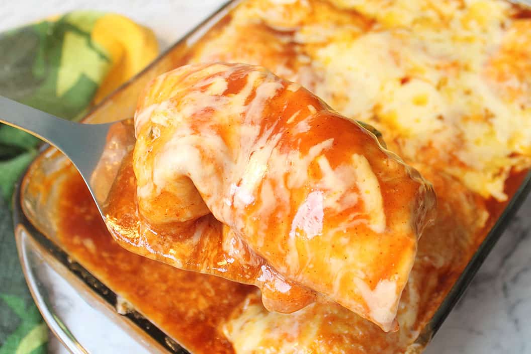 Lifting enchilada out of baking dish.