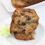 Stack of halved banana bread slices on white plate with yellow flower.