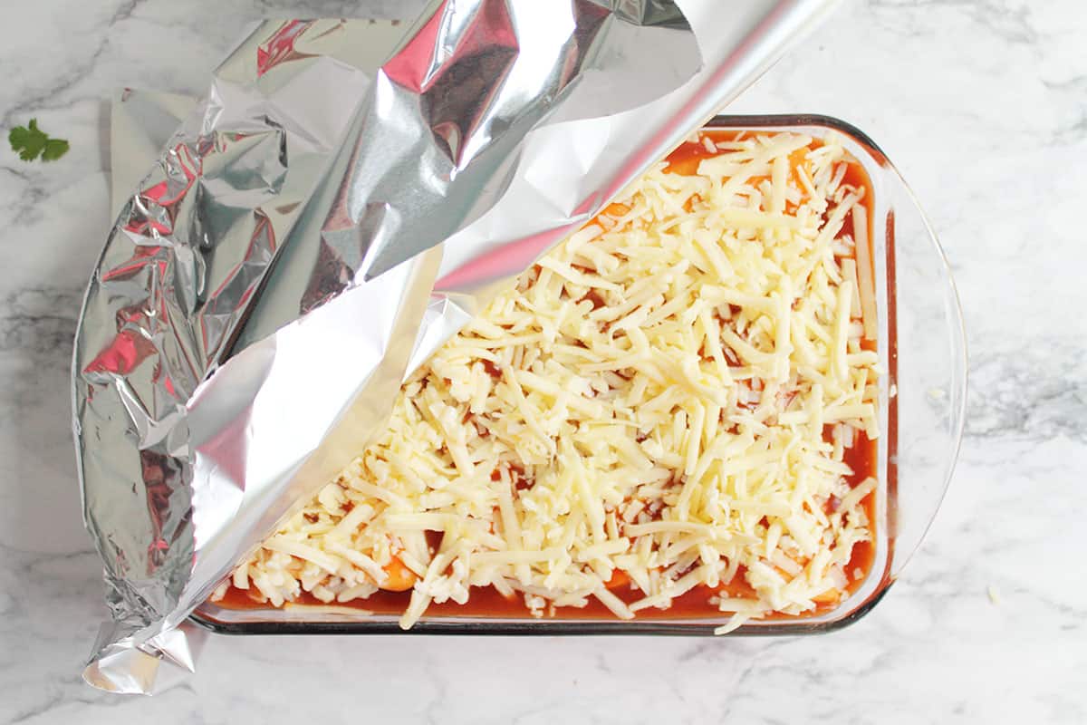 Covering enchiladas with foil to bake.