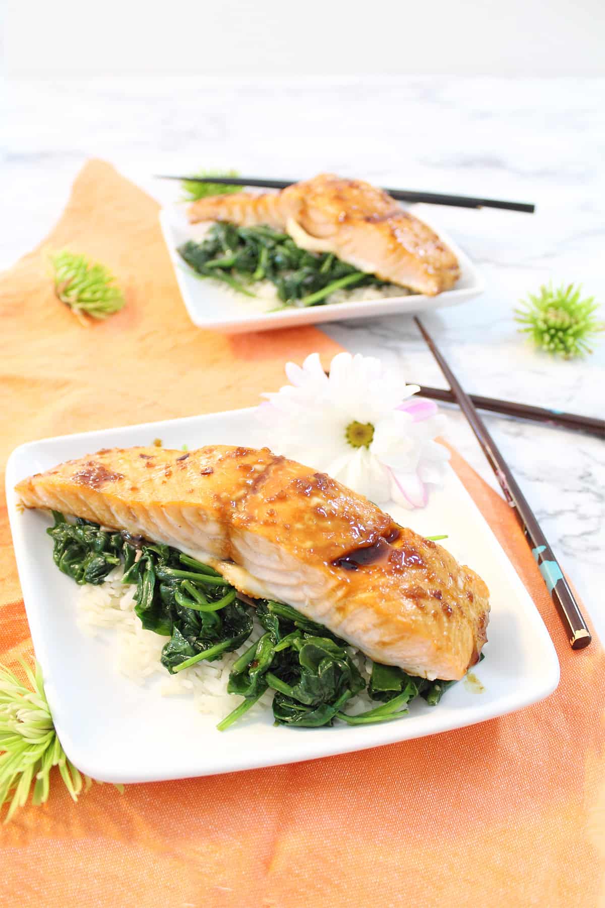 2 servings of salmon dinner on white plates and peach napkin.