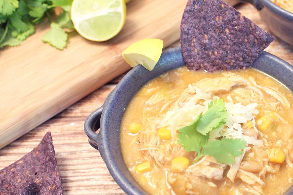 Closeup of partial bowl with lime and cilantro in background.