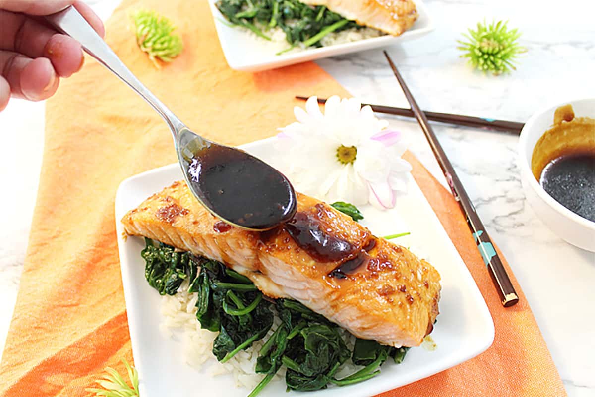 Drizzling maple glaze on baked salmon.