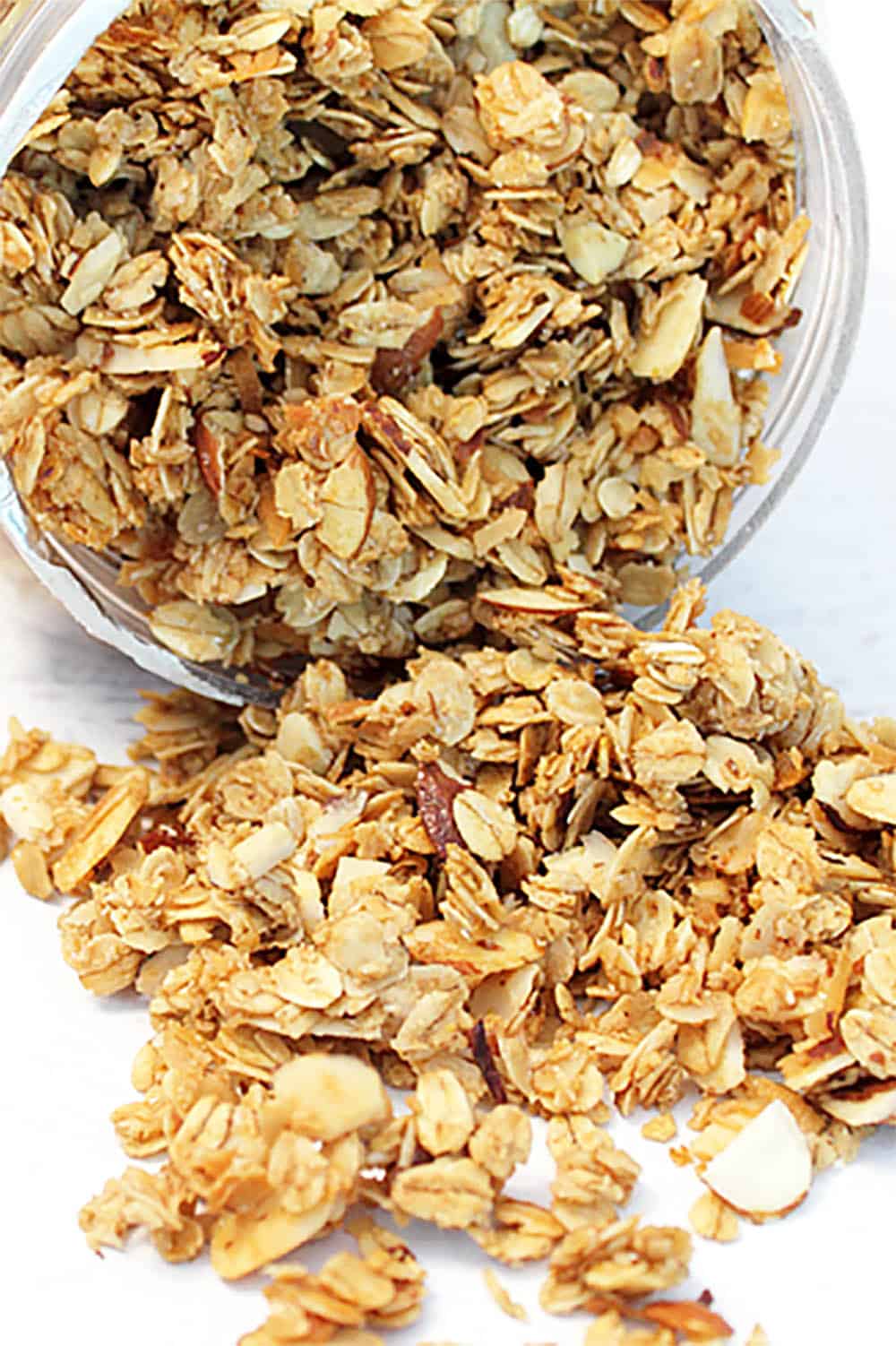 Granola spilling out of container onto white table.