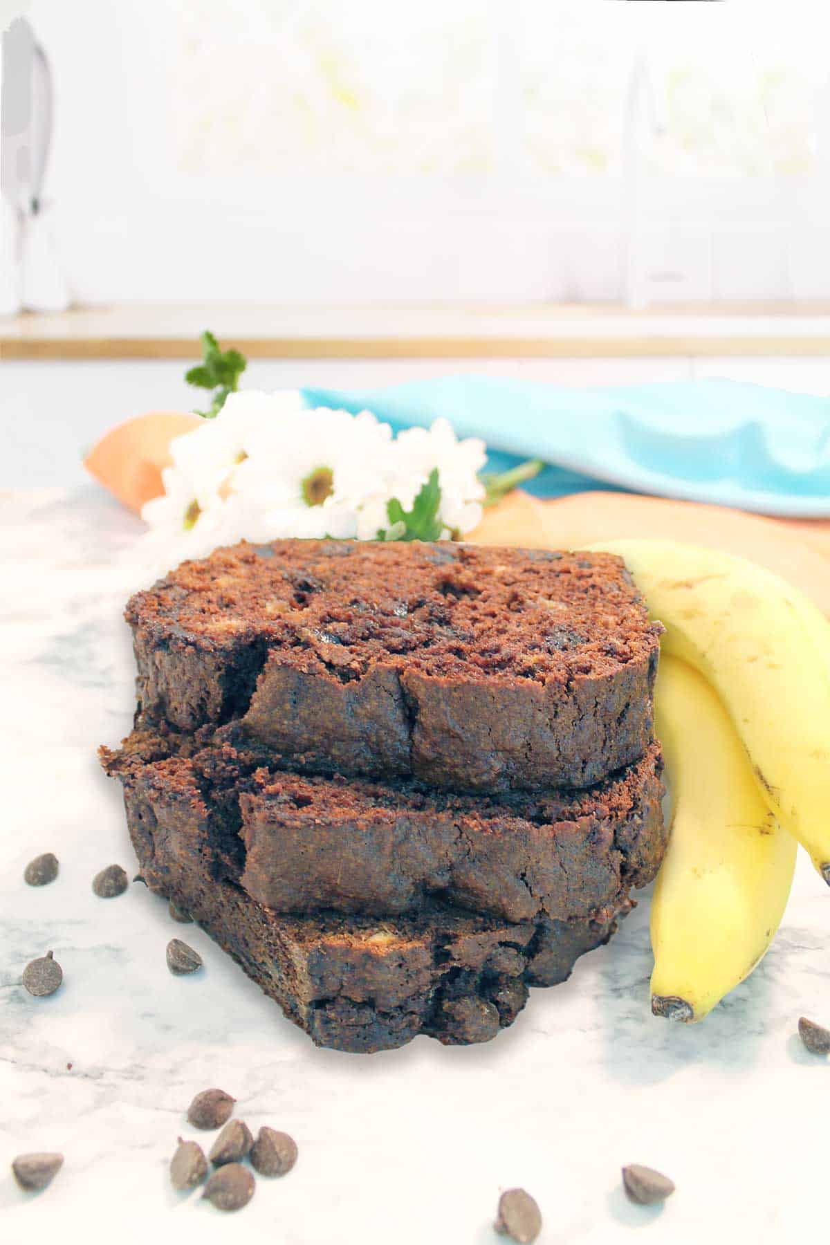 Stack of banana bread slices with chocolate chips and bananas.