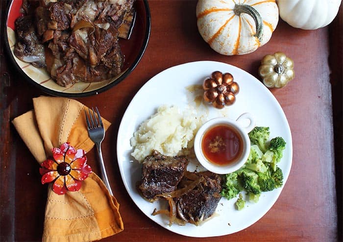 Beef Short ribs dinner plated on white plate with bowl of ribs to the left.