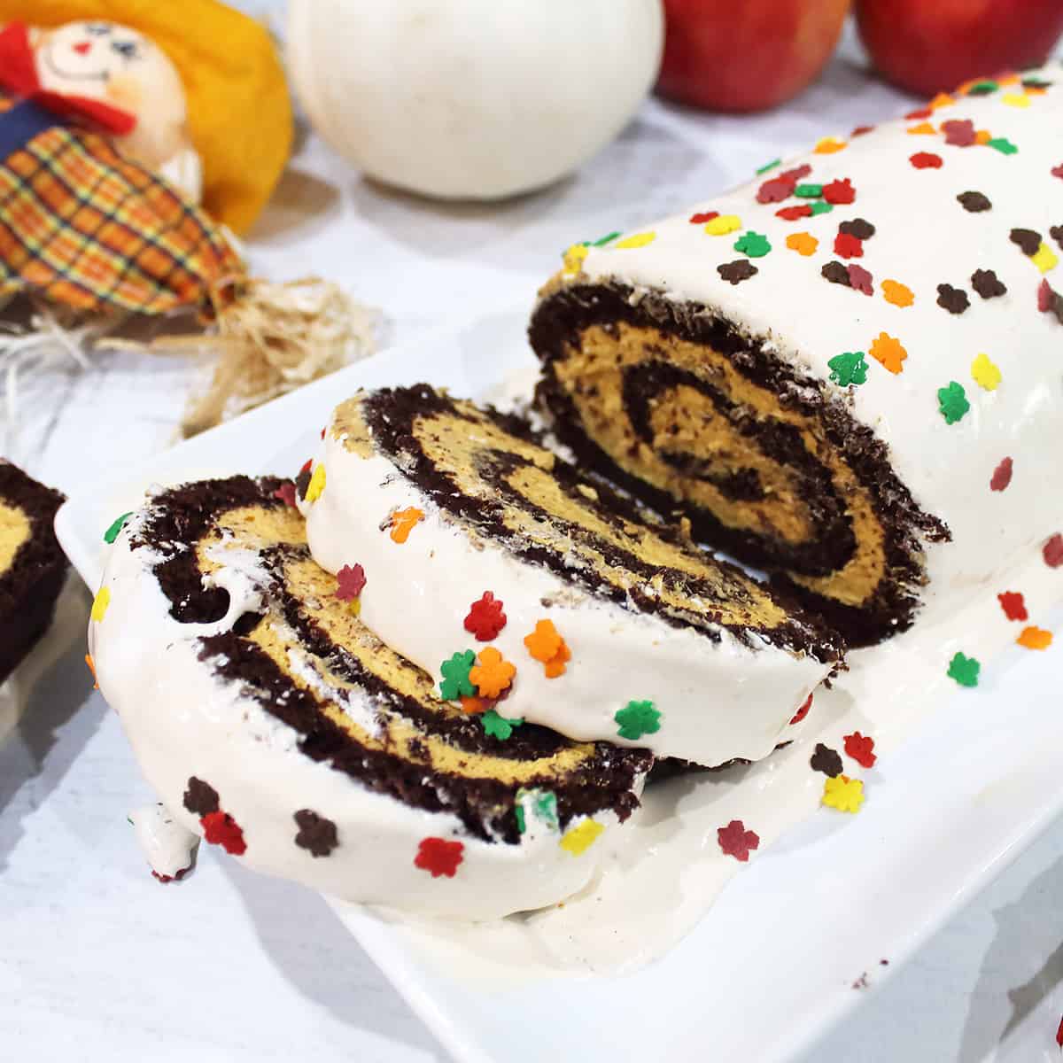 Closeup of two slices of pumpkin roll cake on white platter.