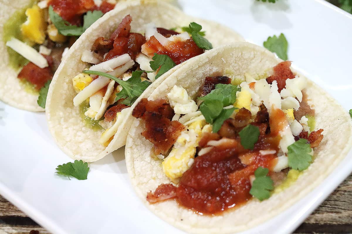 Closeup of breakfast tacos on white platter.