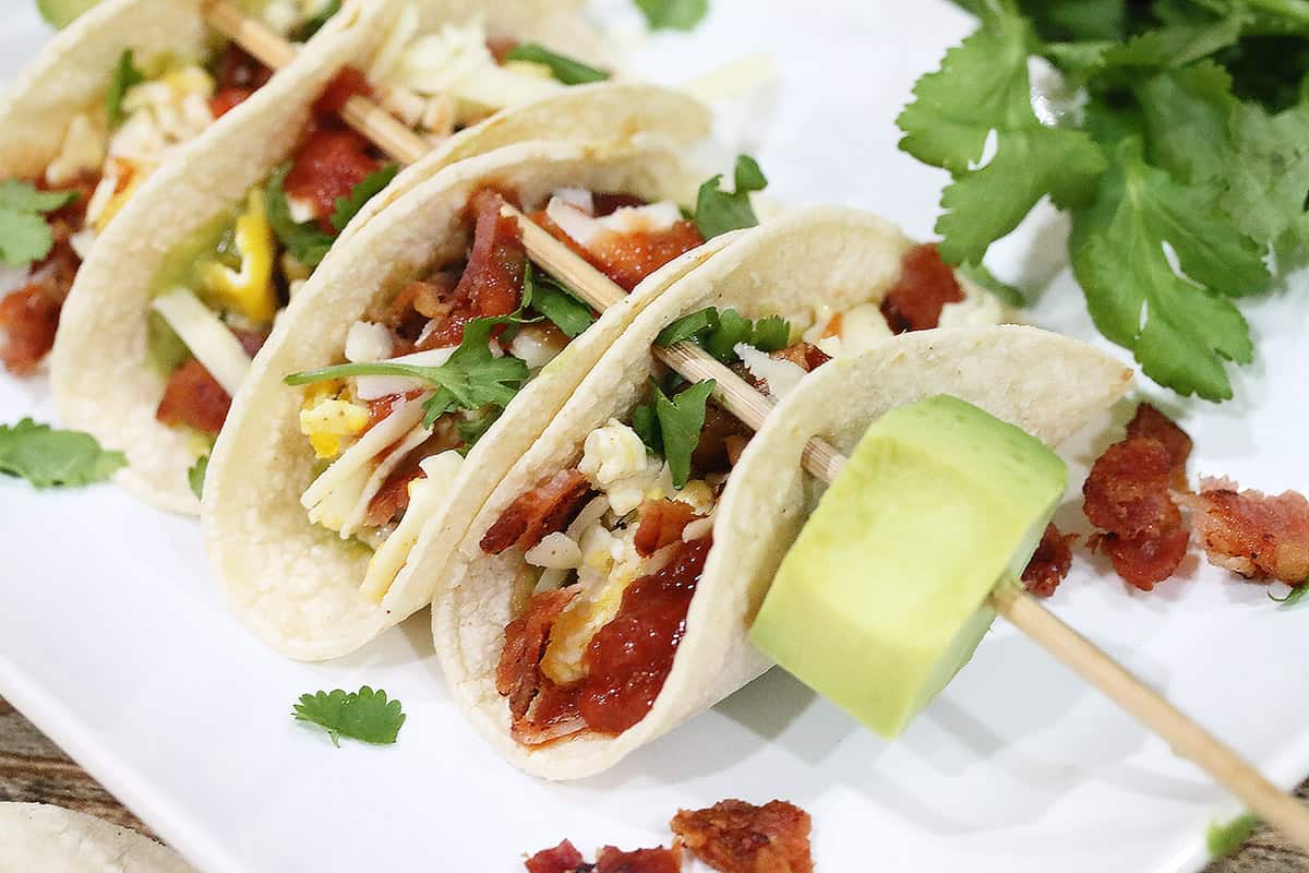 Closeup of skewered breakfast tacos with avocado.