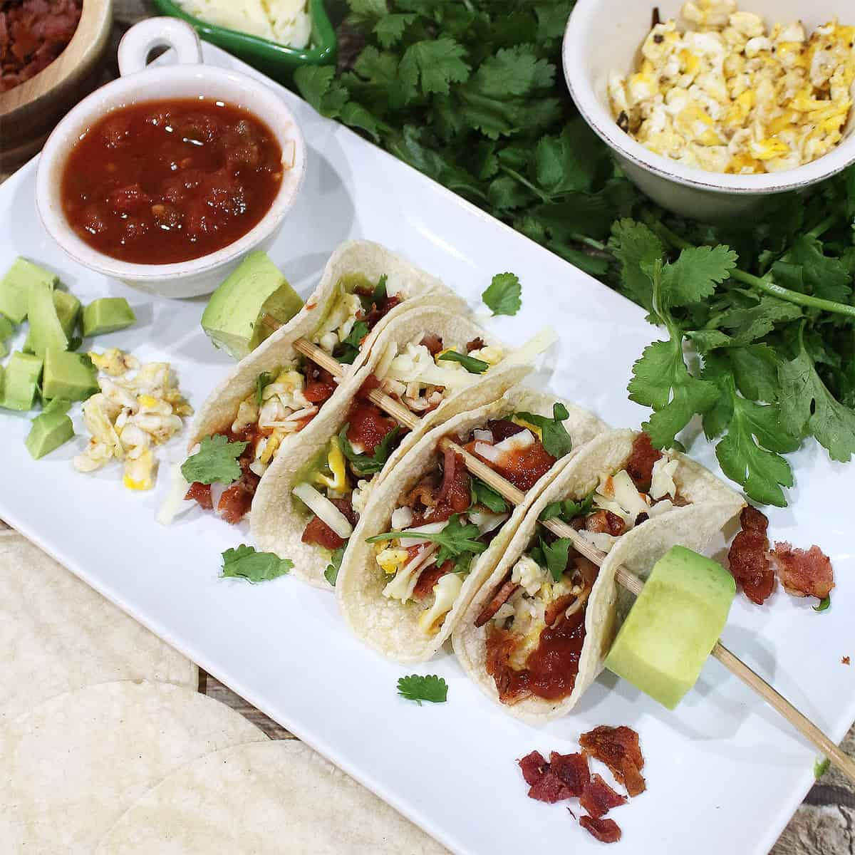 Tacos on skewer on white platter.