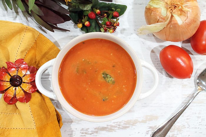 Tomato Basil Soup in white bowl with gold napkin.