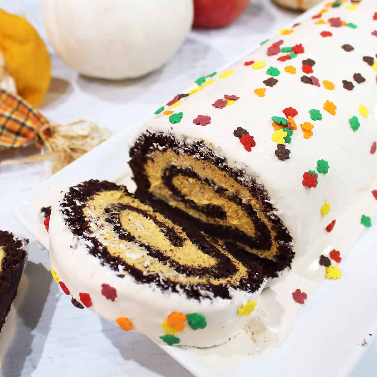 Closeup of slice of cake on cake platter with roll cake.