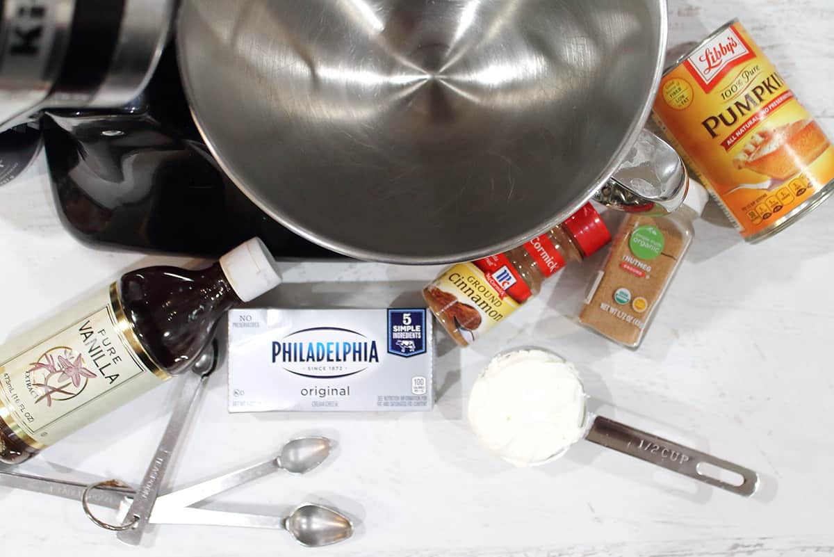 Ingredients for pumpkin cream cheese filling on white table with mixer.