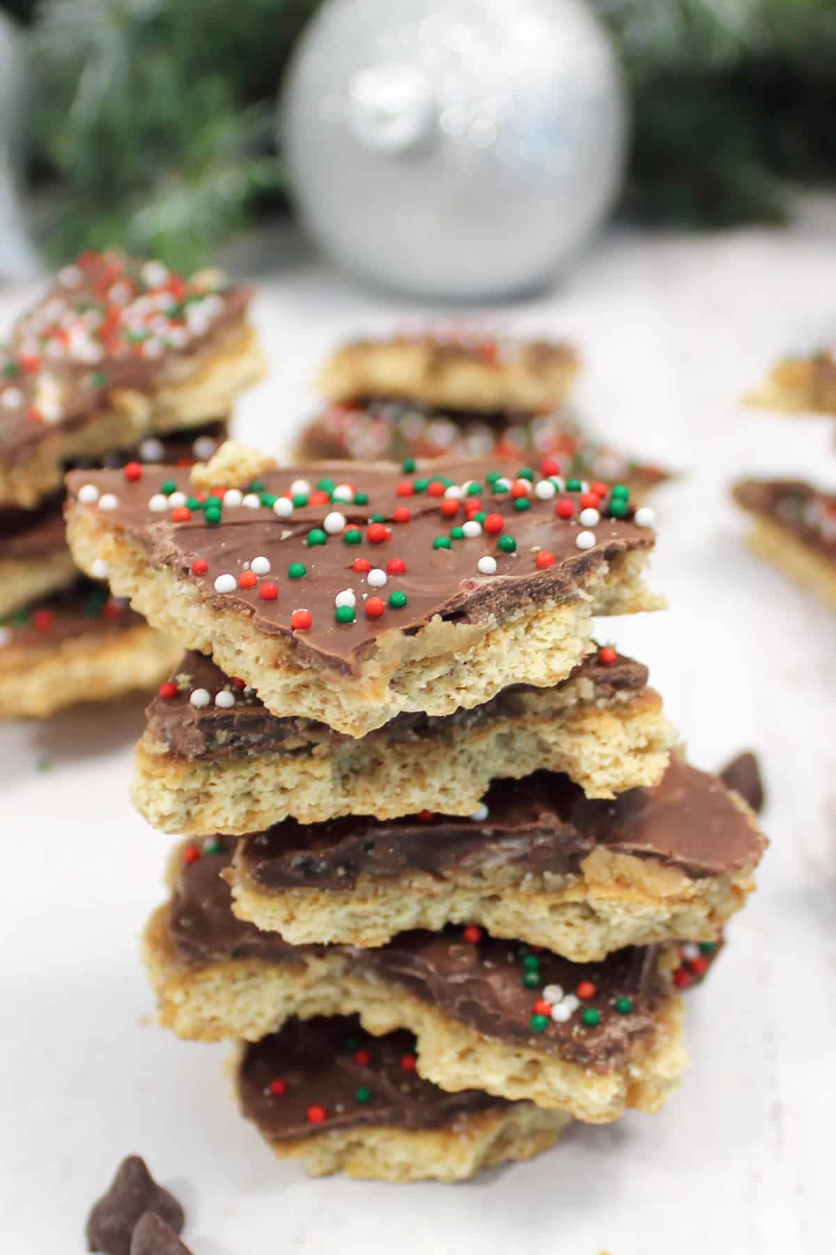 Closeup of stack of s'mores crack with graham crackers with chocolate chips and ornament around.