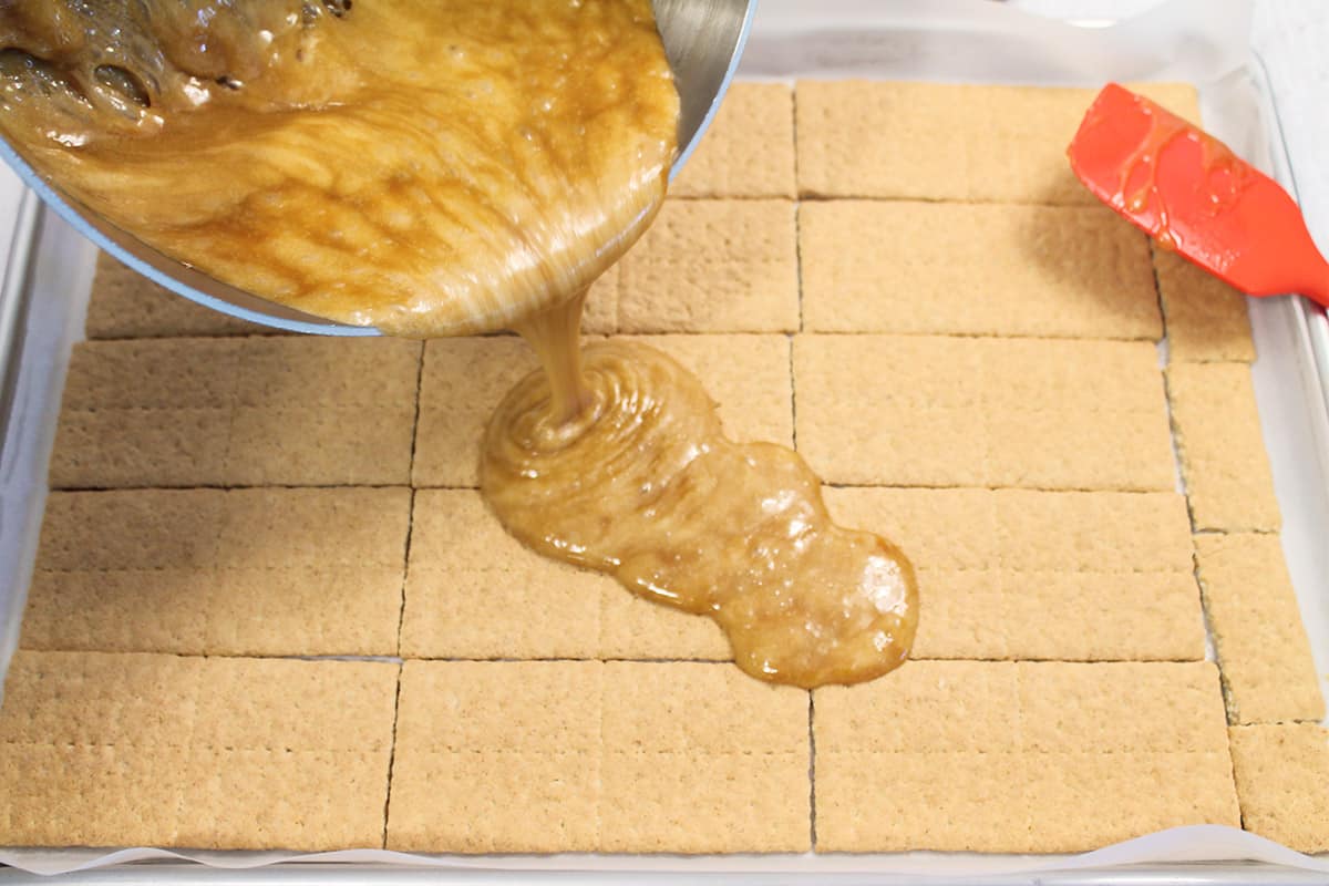 Pouring toffee over graham crackers.
