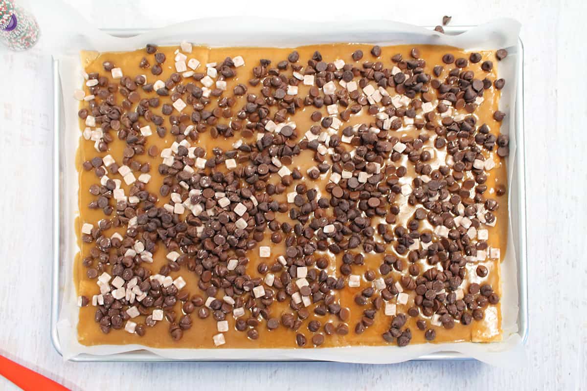Chocolate chips and marshmallows sprinkled over hot toffee.