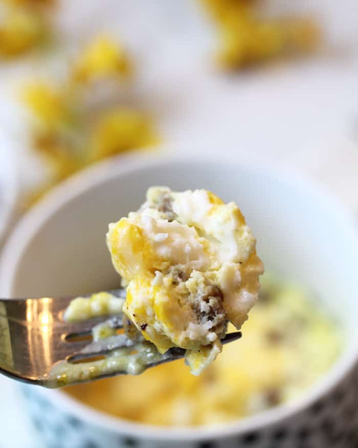 Closeup bite of cooked eggs, sausage and cheese.