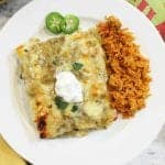 overhead of smothered green chile chicken burritos on white plate with spanish rice.