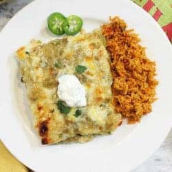 overhead of smothered green chile chicken burritos on white plate with spanish rice.
