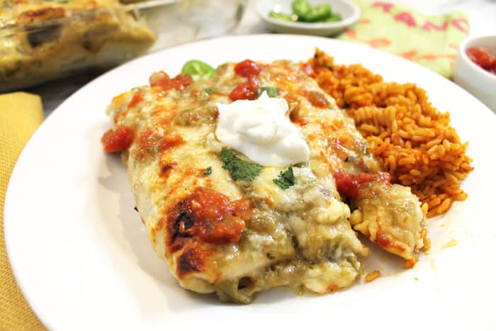Plated burritos on white plate and topped with sour cream.