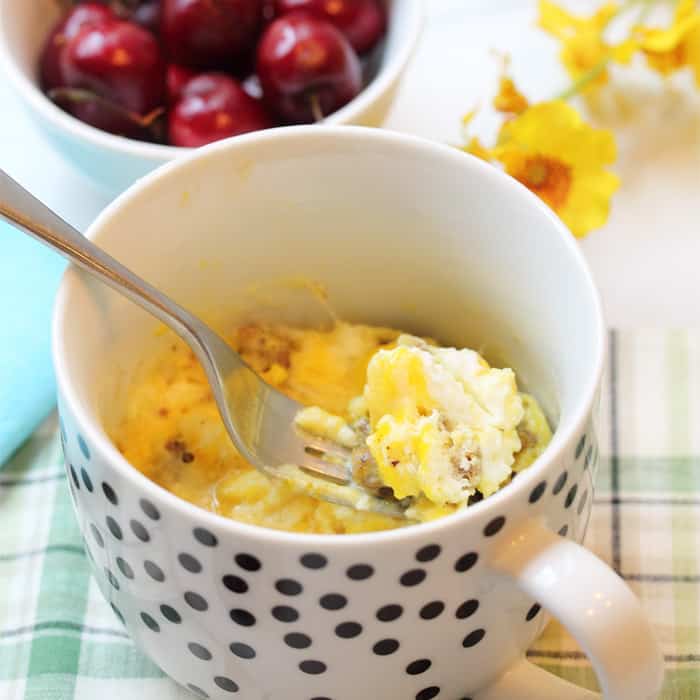 Spoonful of egg breakfast with cherries and yellow flowers.