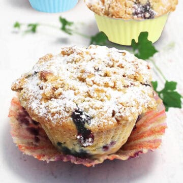 Blueberry muffin with lemon with liner pulled back.