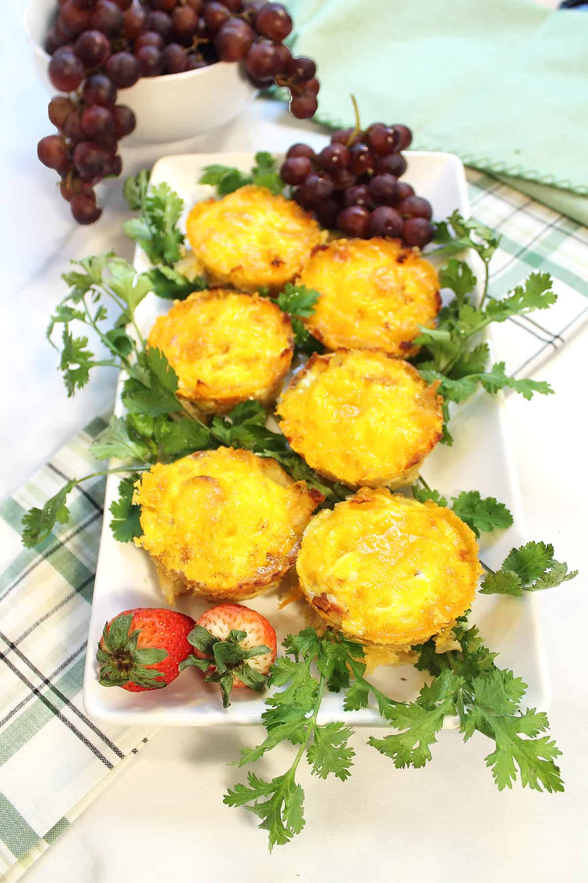 Egg Cups on platter with strawberries and parsley with grapes in background.