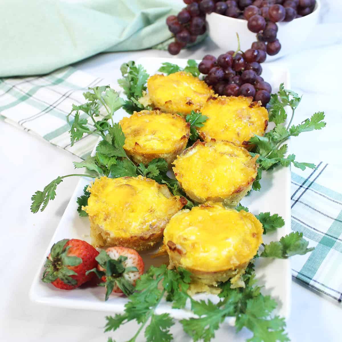 Egg Cups on white platter with parsley garnish laying on green and white checkered napkin.