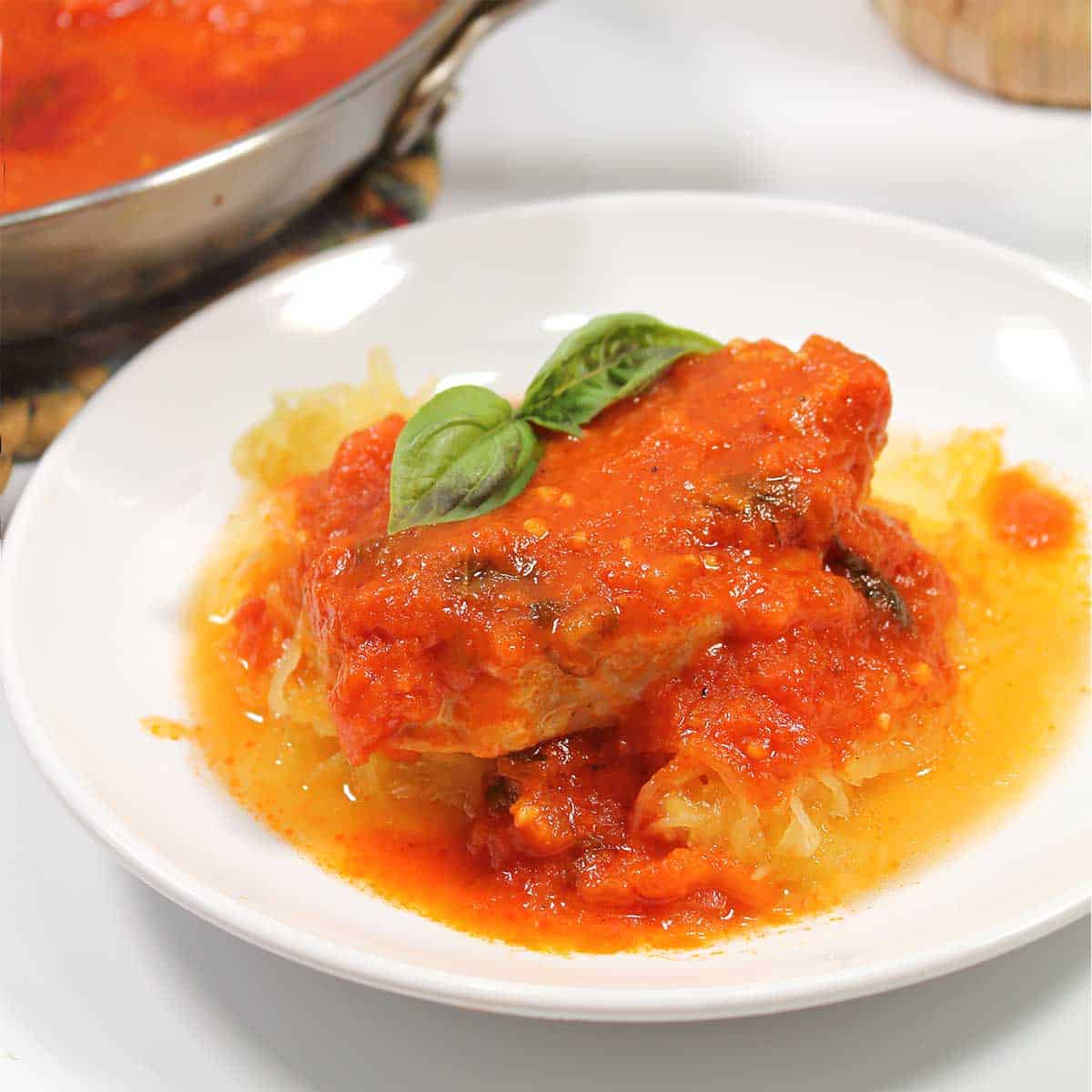 Closeup of Italian pork chop on top of spaghetti squash.