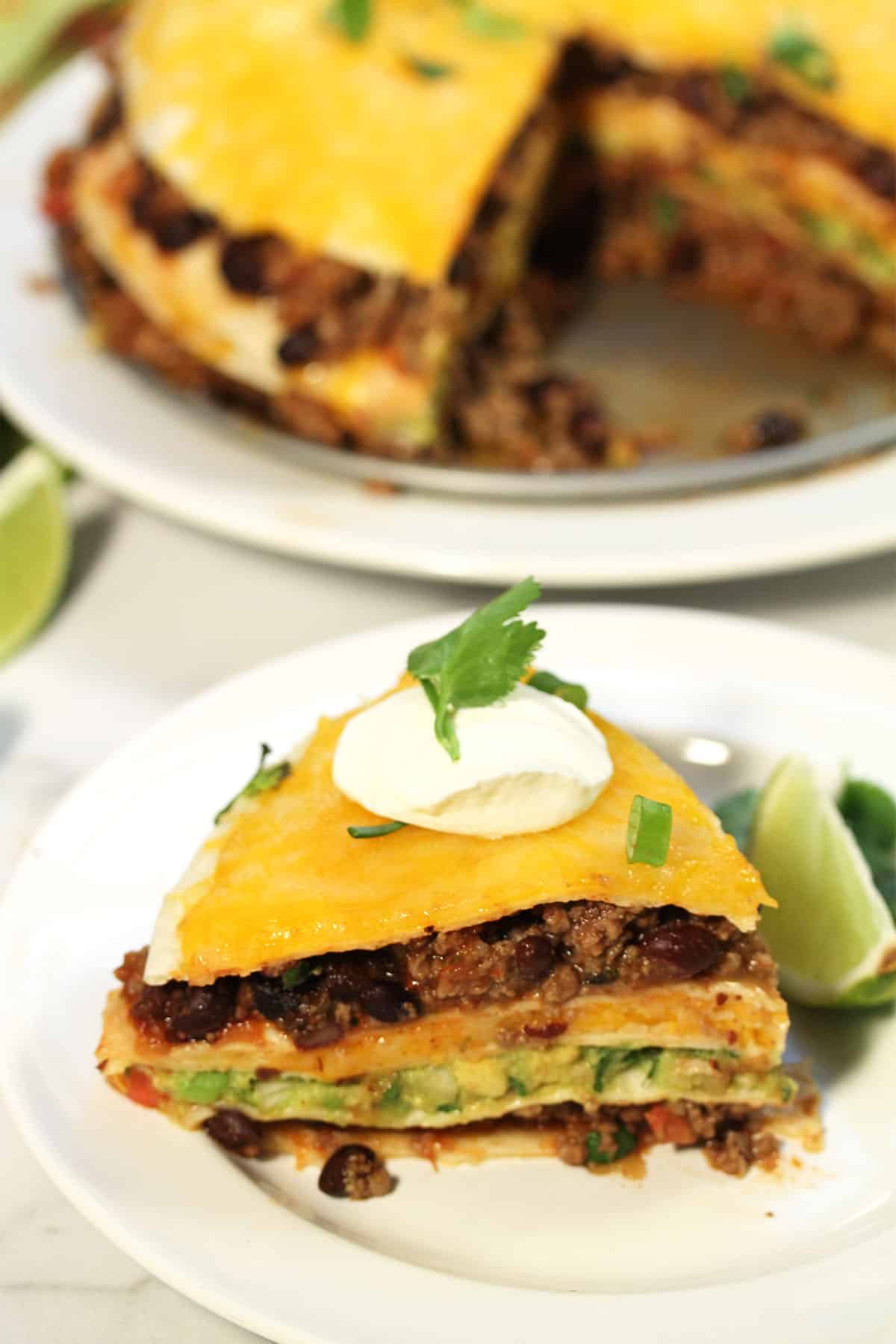 Slice of tortilla stack on white plate with stack in background.