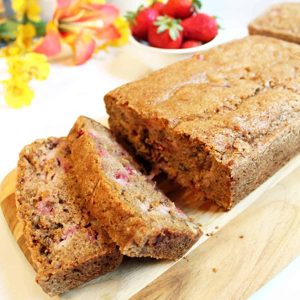 Closeup of sliced bread with bowl of strawberries in back.