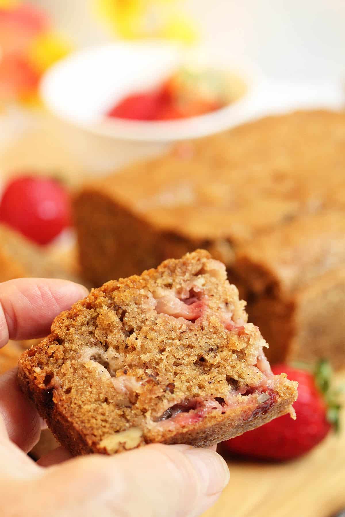 Holding a slice of fresh strawberry bread.