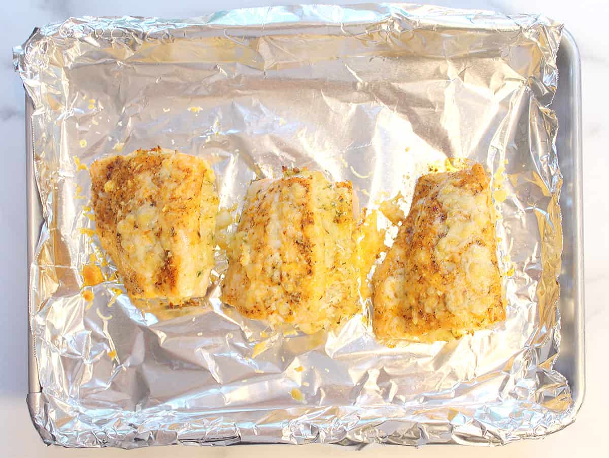 Browned cooked salmon on foil-lined baking sheet.