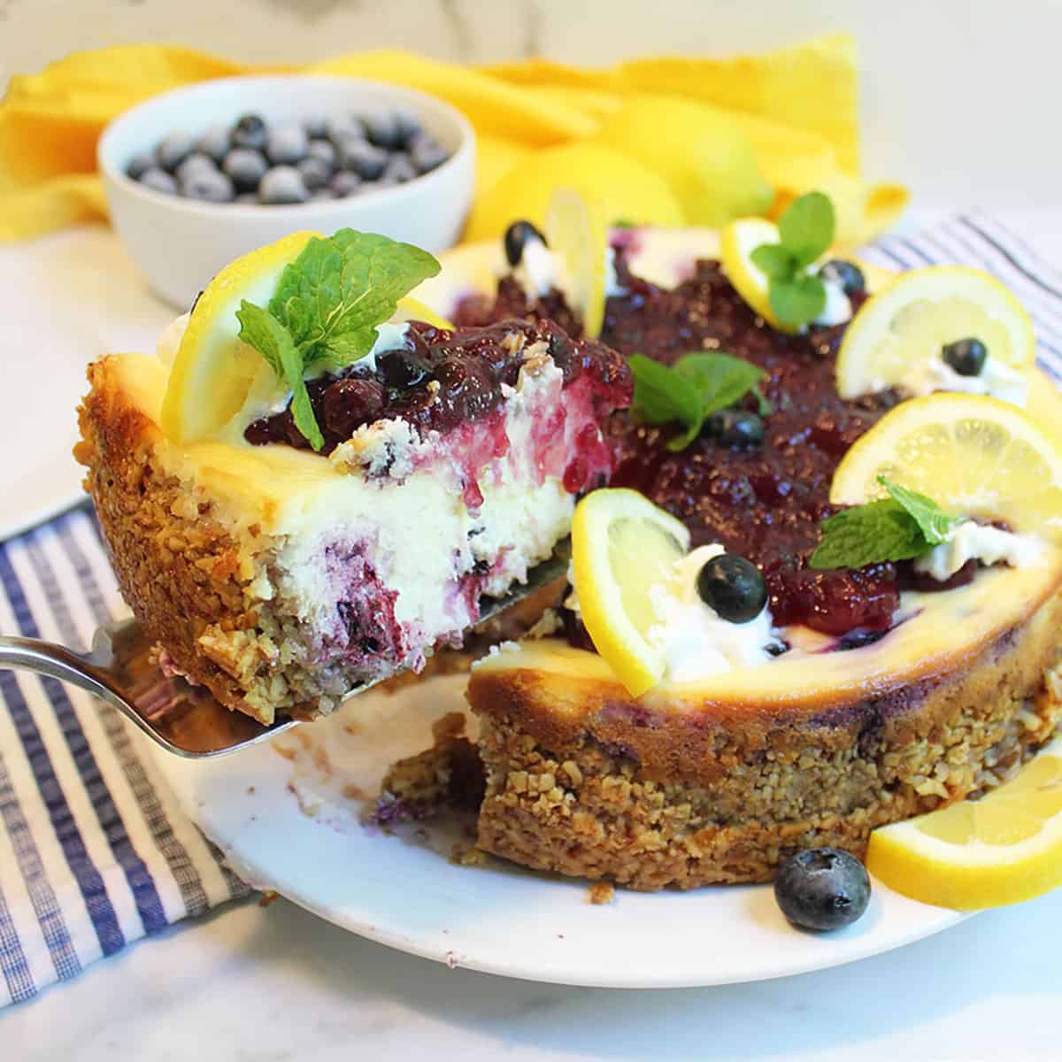 Lifting out slice of cheesecake with yellow napkin in background.