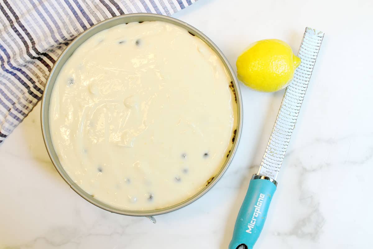 Ready to bake cheesecake next to lemon and zester.