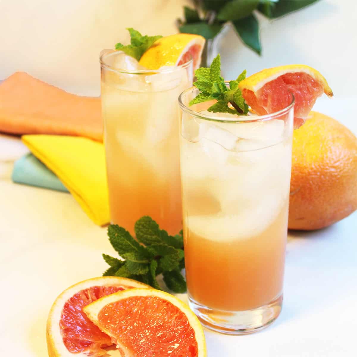 Ready to drink cocktails on white table with grapefruit slices in front.