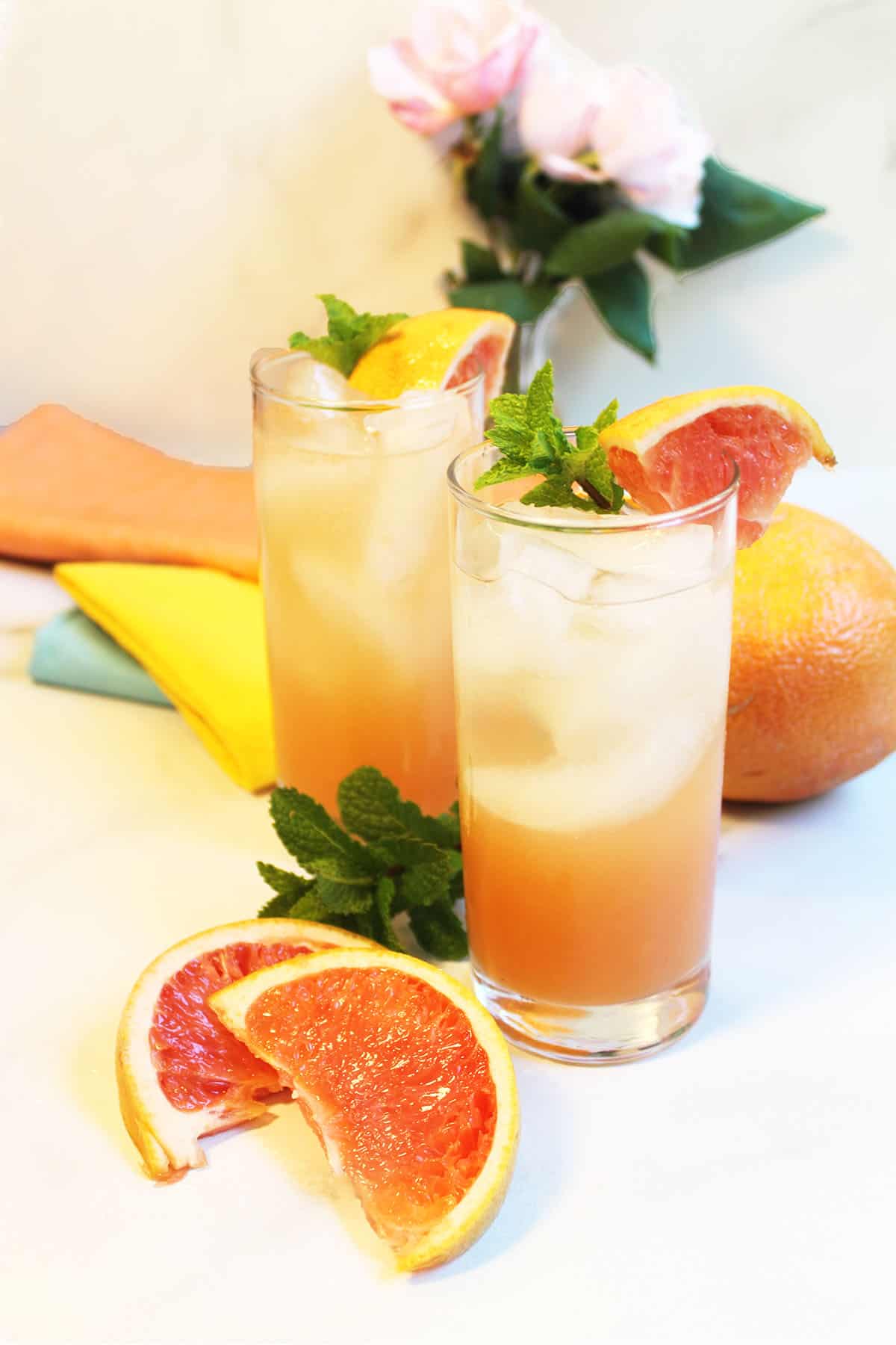 Ready to drink cocktails on white table with grapefruit slices in front.