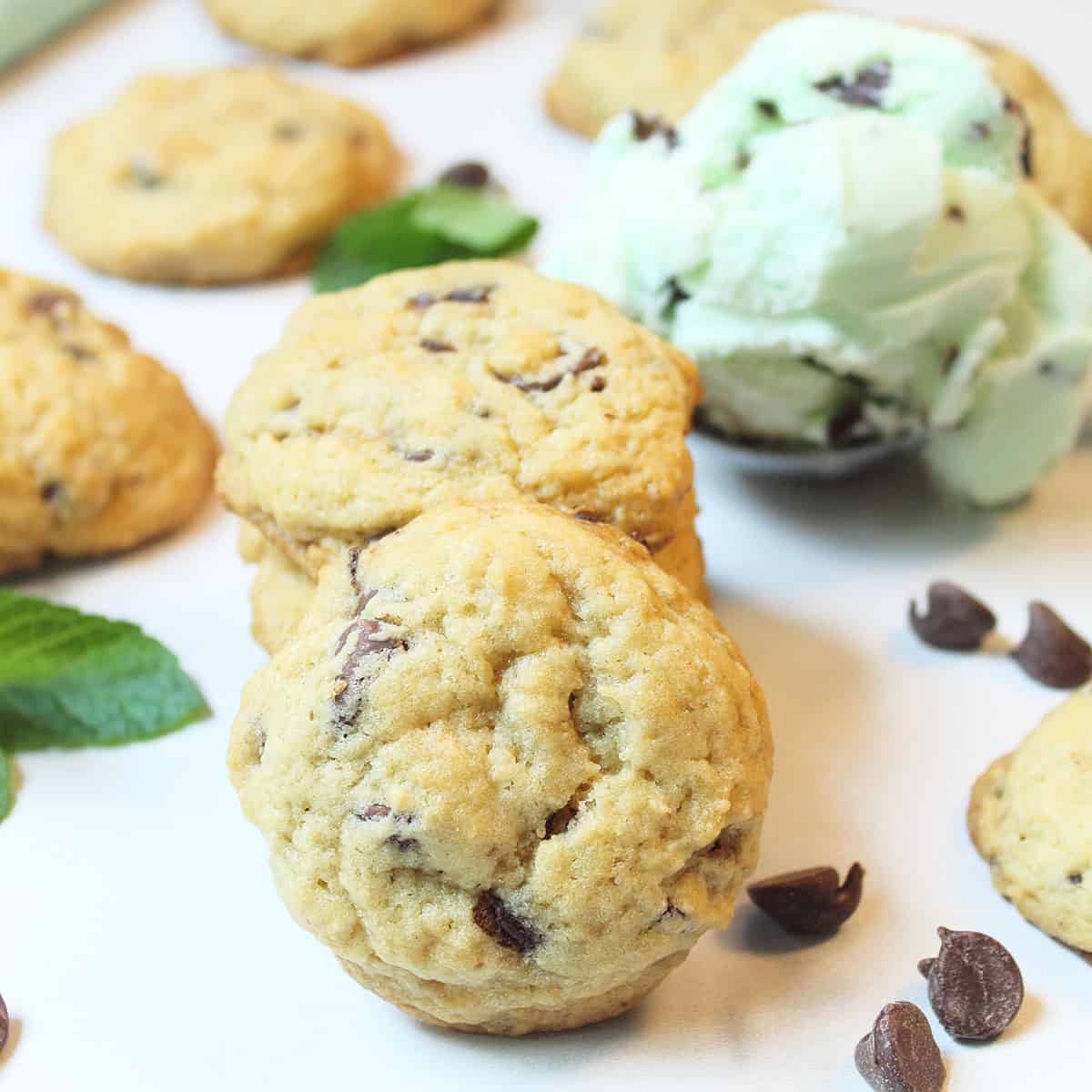 Stack of cookies with other cookies and chips scattered around with scoop of ice cream.