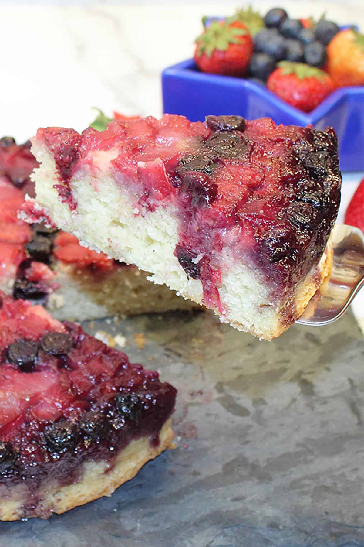 Closeup of slice on server with star filled with strawberries and sparkler streamers in back.