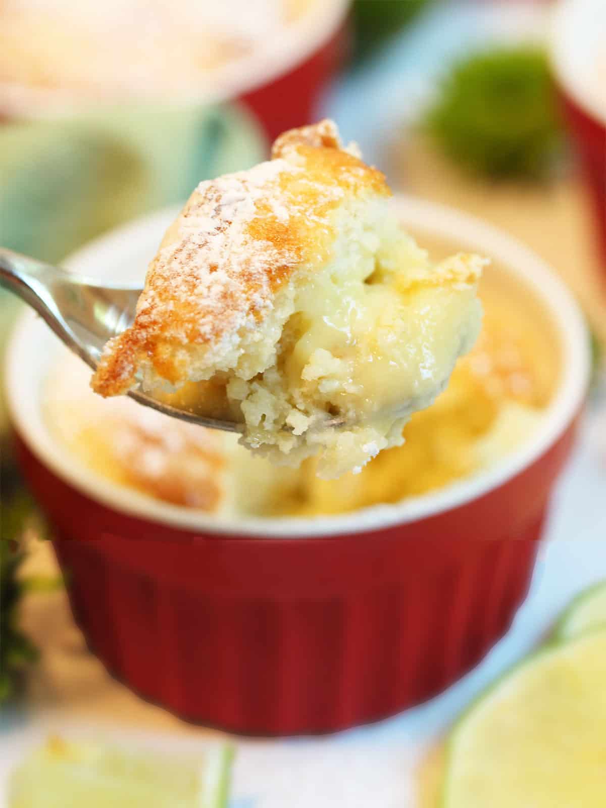 A bite of pudding cake above ramekin.