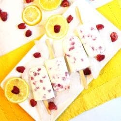 Overhead of lemon posicles on white platter with ice on yellow napkin.