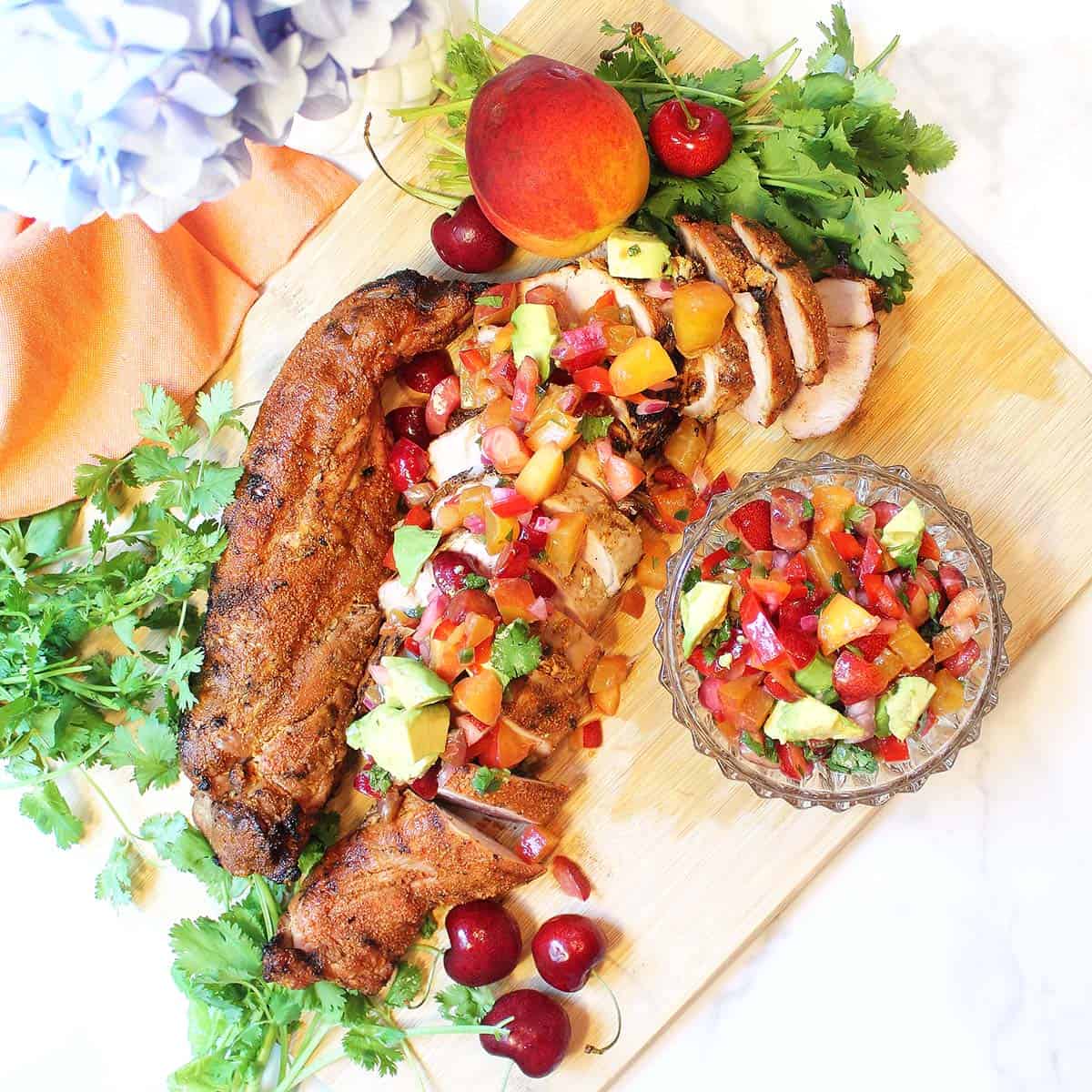 Dinner is served! Cherry salsa on grilled pork on wooden cutting board.