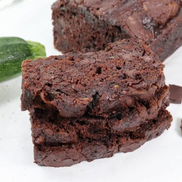 Stacked slices of chocolate chocolate zucchini bread with loaf in back.
