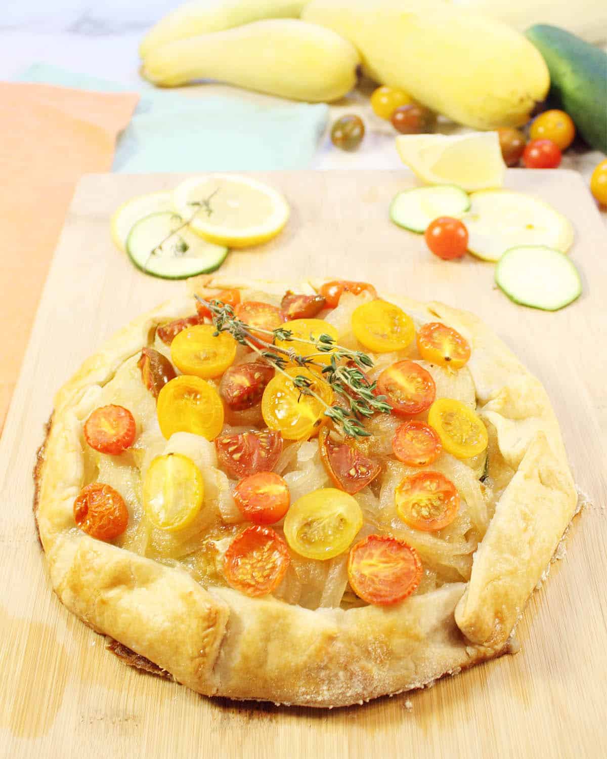 Finished tart on cutting board with squash in background.