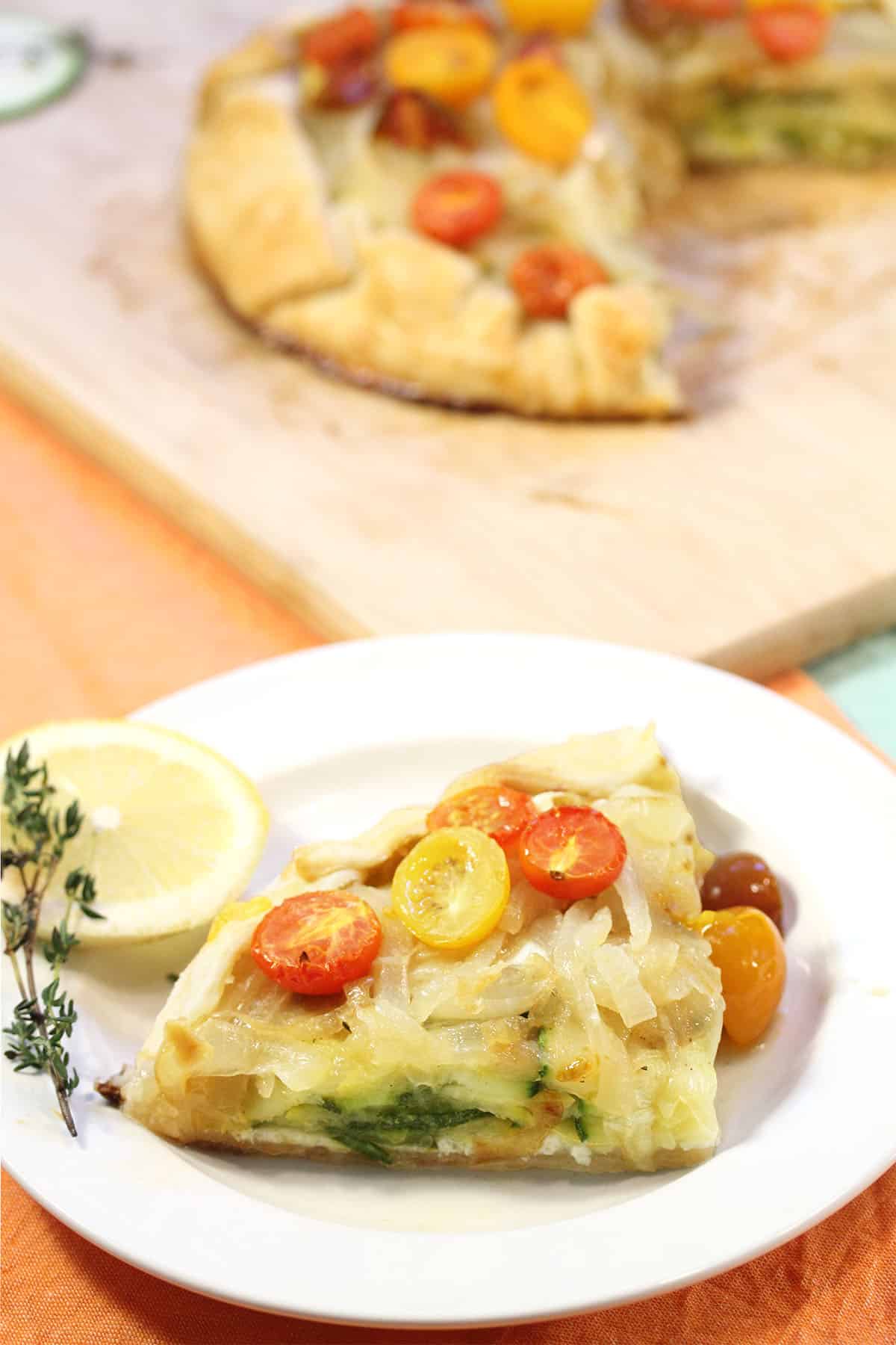 Slice on white plate with whole galette on wooden board in background.
