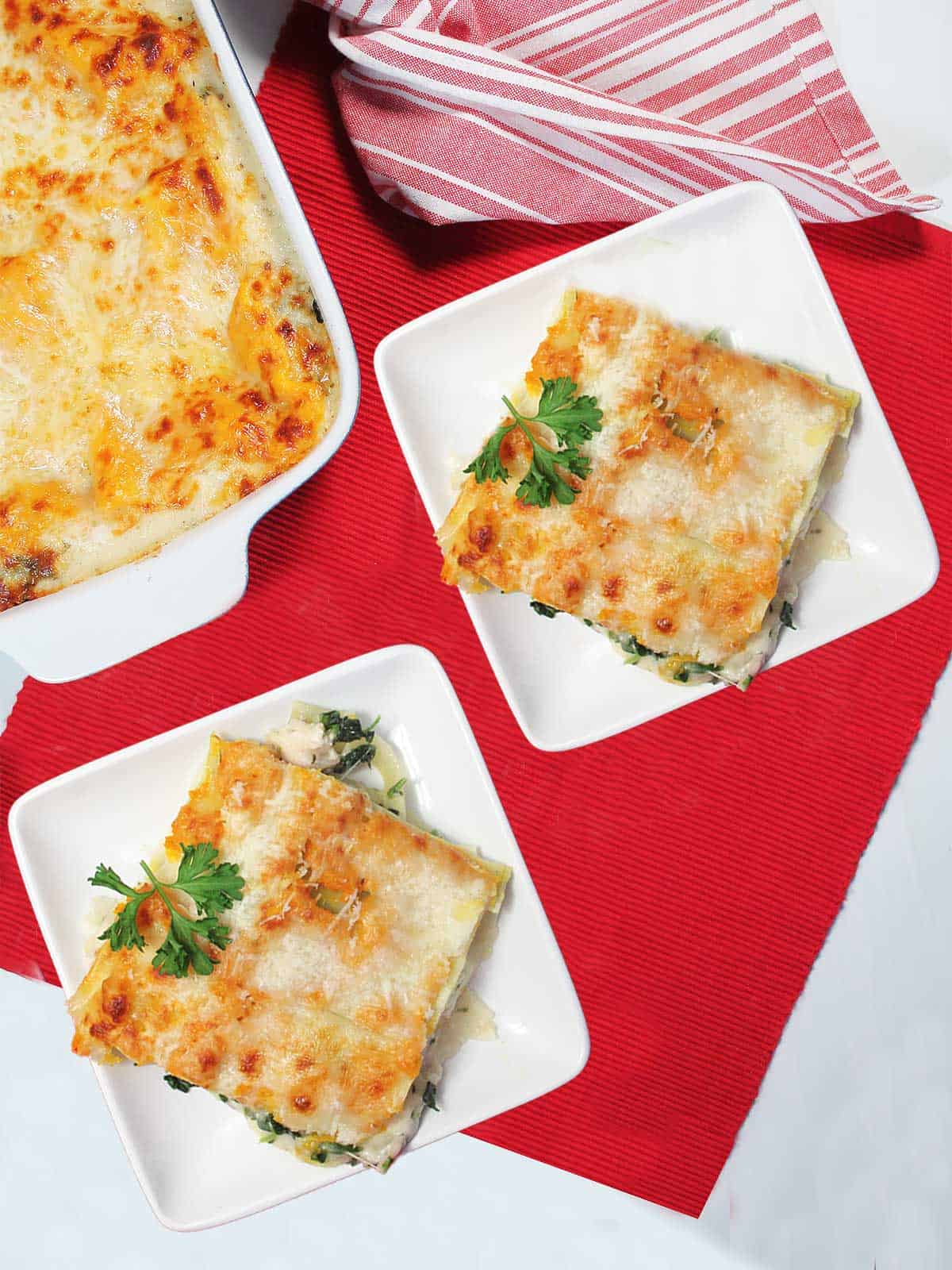 Two servings of chicken lasagna plated with parsley garnish.