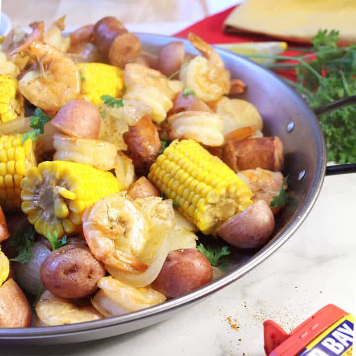 Partial view of low country boil in round pan with parsley.